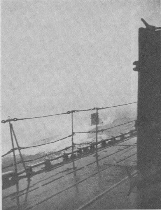 U-Boat partially awash alongside a ship, only its conning tower visible.