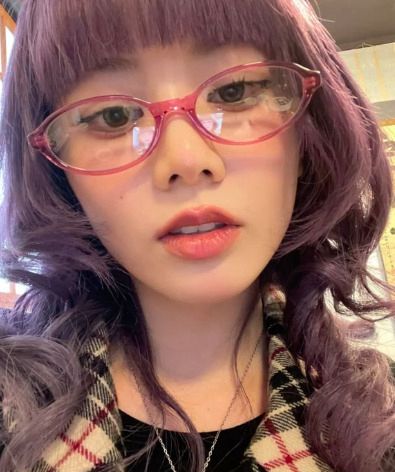 selfie from hinata from xg with purple hair and red oval glasses 