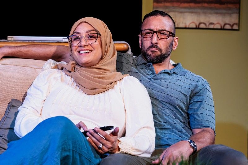 A couple sits together on a couch.