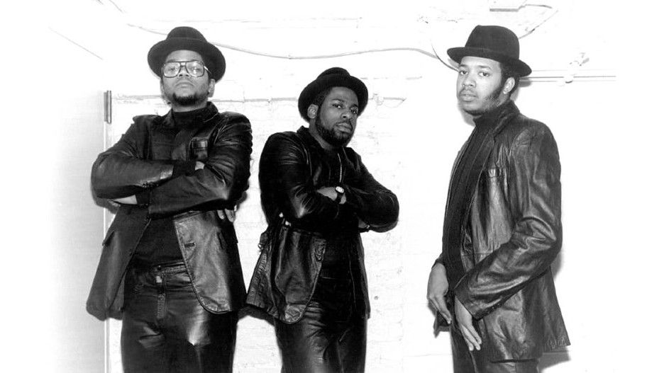 The three members of Run-D.M.C. wear black fedora hats and leather jackets