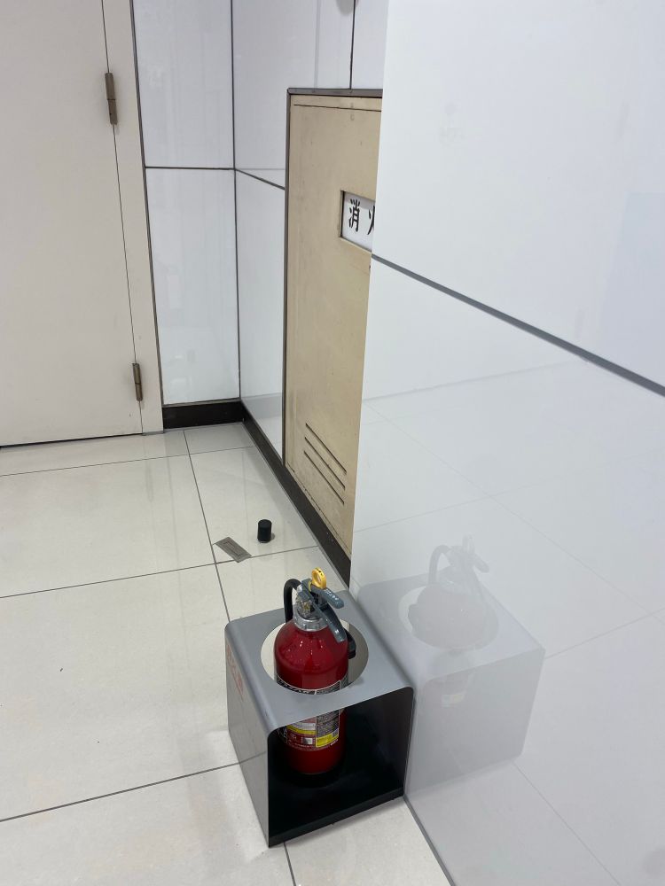 Fire extinguisher in a small enclosure on the ground