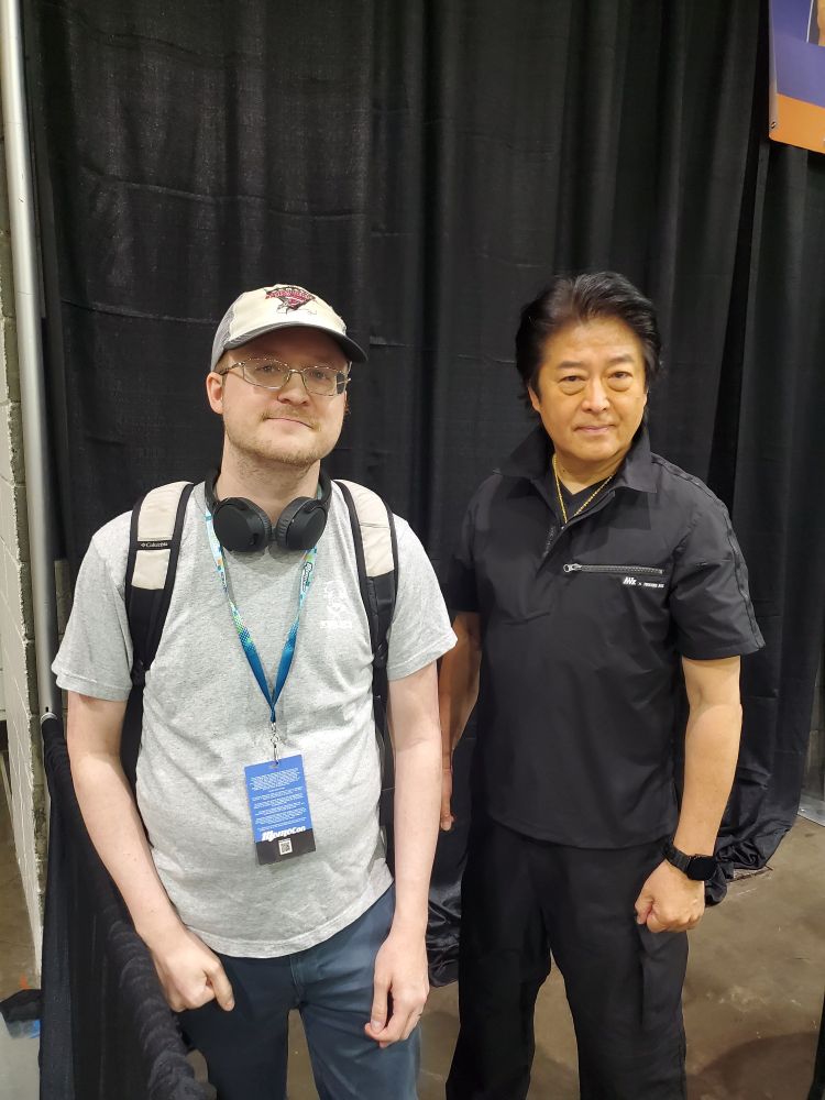 I stand awkwardly next to Shiro Izumi with a crooked smirk (an attempted smile) on my face.