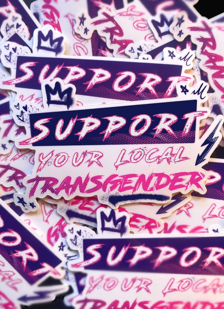A sticker that says ‘support your local transgender’ in a tag/graffiti like style 