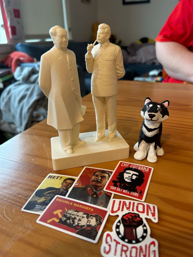 A 3D printed sculpture of Mao and Stalin. The former stands with his hands behind his back in the traditional Chinese uncle way while the latter puffs on his famous pipe. There is also a bonus sculpture of my late Shiba Inu, nori. They are surrounded by various communist stickers 