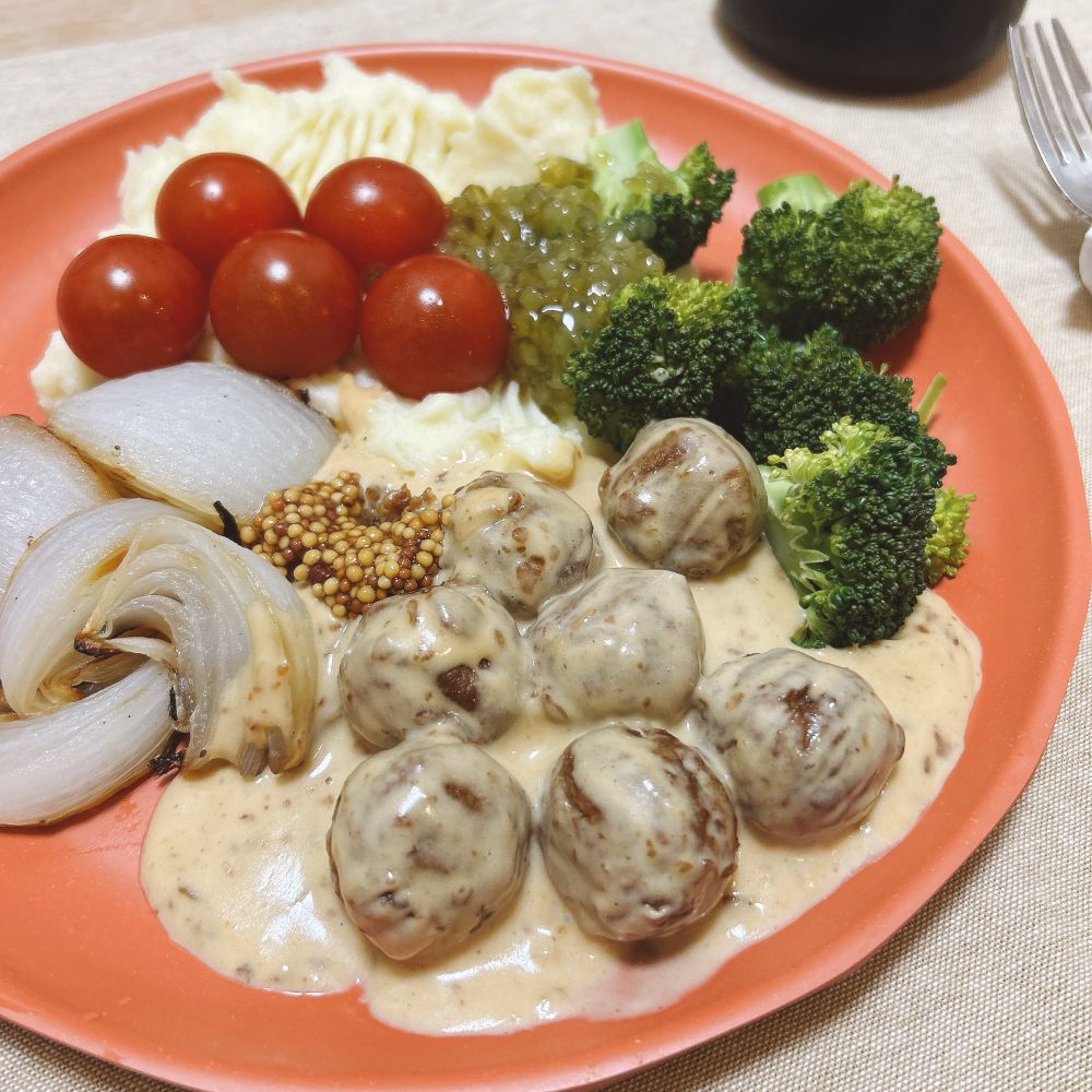 朱色の丸皿に料理が盛られている
左上から時計回りに
マッシュポテト
プチトマト５つ
焼いたくし切りの玉ねぎ
ミートボール（クリームソースがけ）
ブロッコリー
ミートボールにはレリッシュと粒マスタードが添えられている