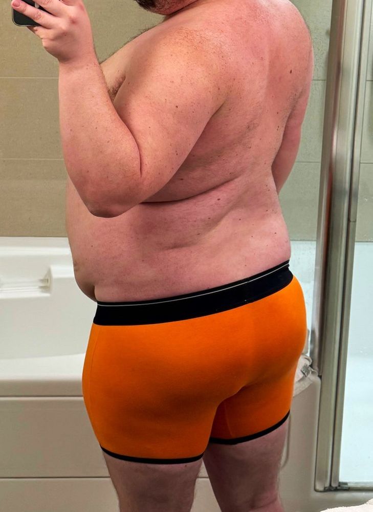Beefy bear shows off his back and his thick butt in an orange pair of boxer briefs