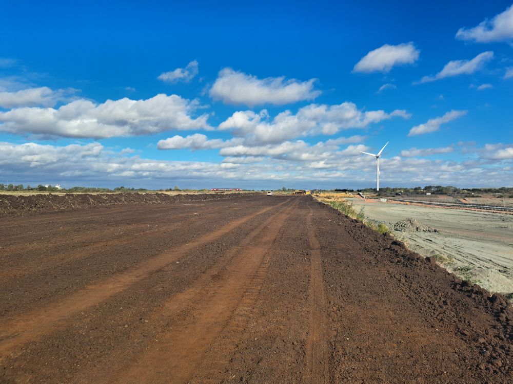 Exposed peat, flat horizon and blue sky with small white fluffy clouds. 