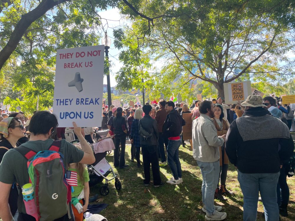 Protestor holds up sign: THEY DO NOT BREAK US THEY BREAK UPON US