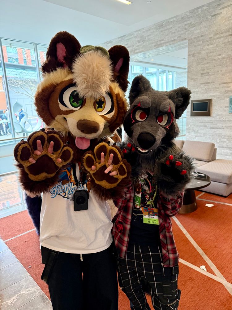 2 fursuiters in a hotel lobby at anthrohio taking a picture together 