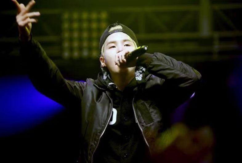 Blond Yoongi with a cap rapping on stage