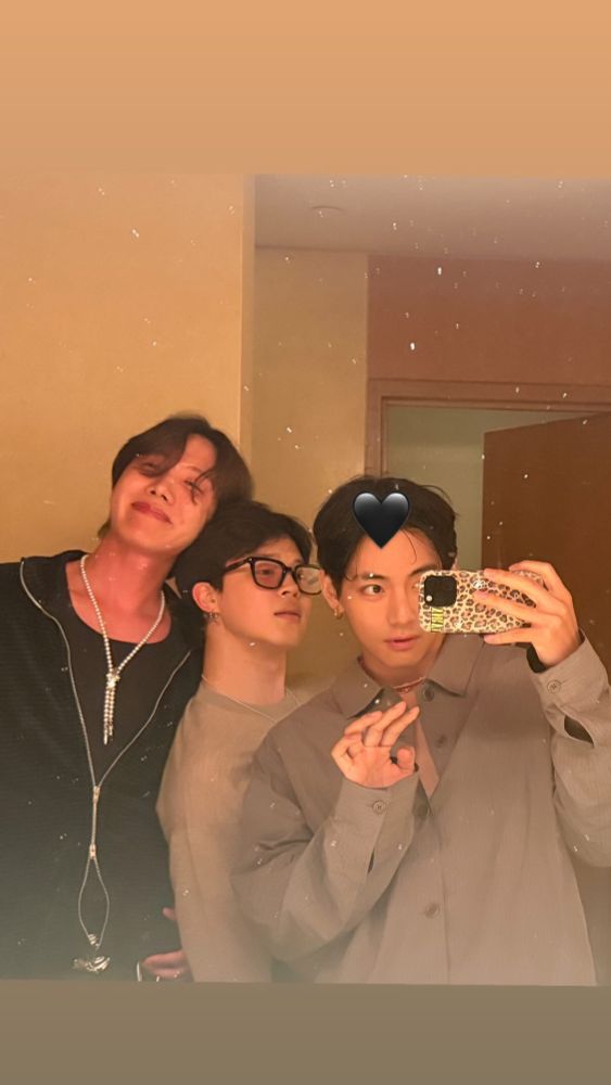 Another selca by Tae of himself, Hobi, and Jimin. They're standing in a room and are taking the photo in front of a mirror. Hobi is flushed red and leaning his head against Jimin. Tae stands in front of them and waves at us. There's a black heart emoji on top of Tae's head