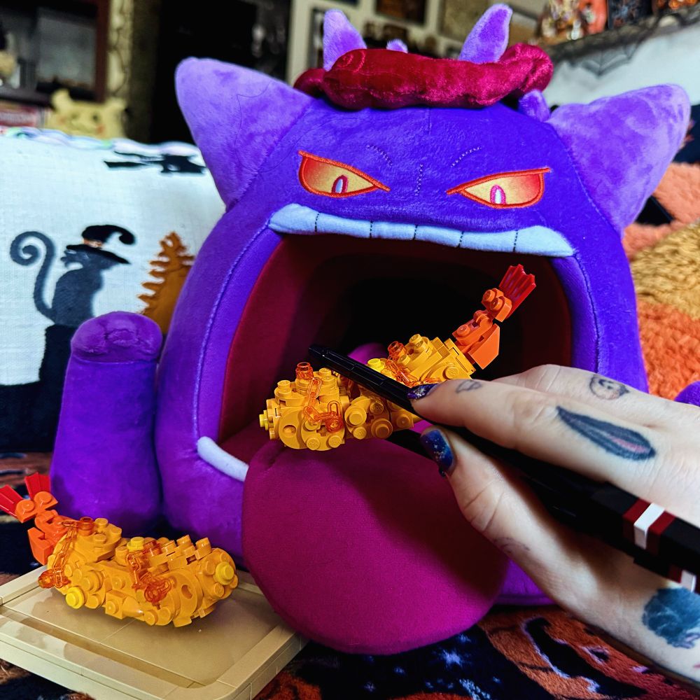 My hand with “lego” chopsticks holding a lego shrimp tempura. It looks like Im feeding it to my gigantimax Gengar plush and there is a second shrimp tempura next to it