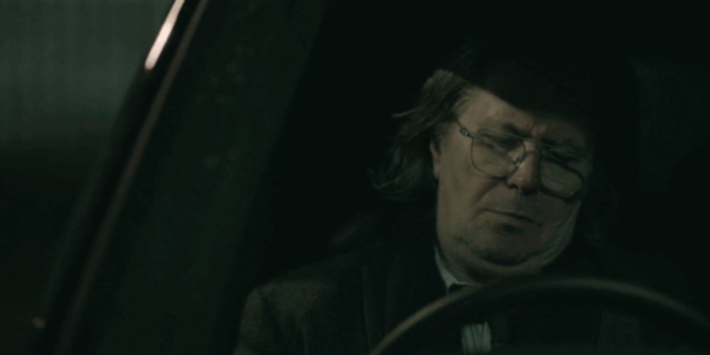 a man wearing glasses is sitting in a dark car