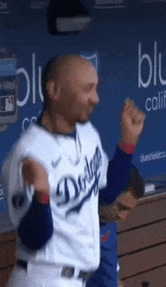 a man in a dodgers uniform is dancing in front of a blue wall