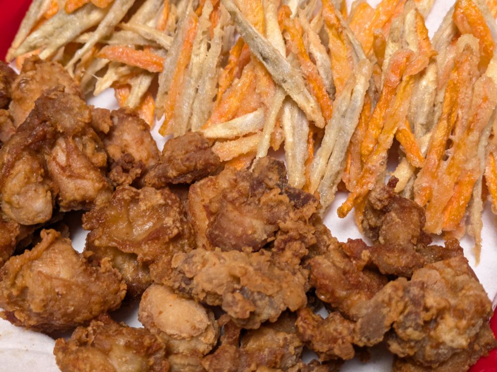 バットの手前に唐揚げ(小さめで味が濃そうな色)、奥ににんじんとごぼうのかき揚げが並ぶ。