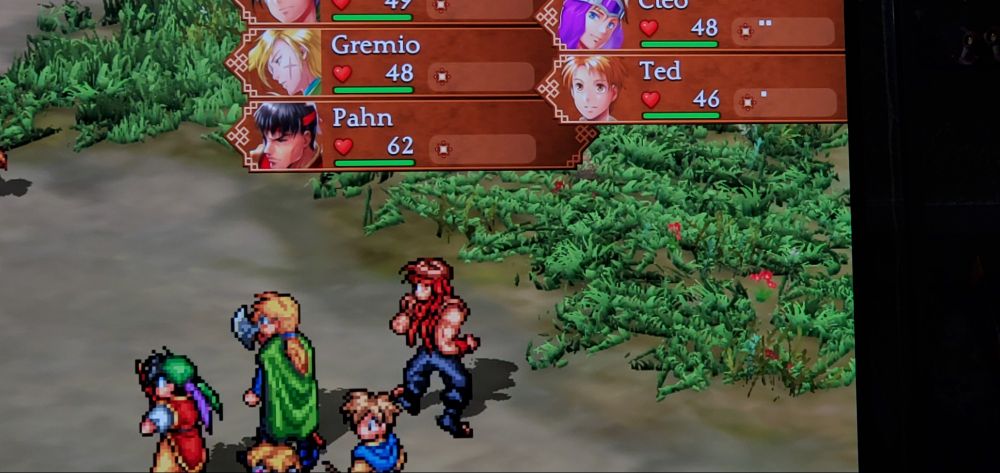 A phone taken picture of a TV. Showing a battle screen of Suikoden Remaster 1, with panes of grass slapped around randomly and low resolution textures.