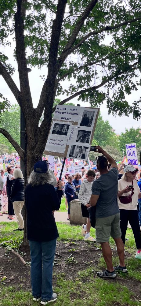 Protest sign with images of MN state representatives who were shot today.  Crowd in background