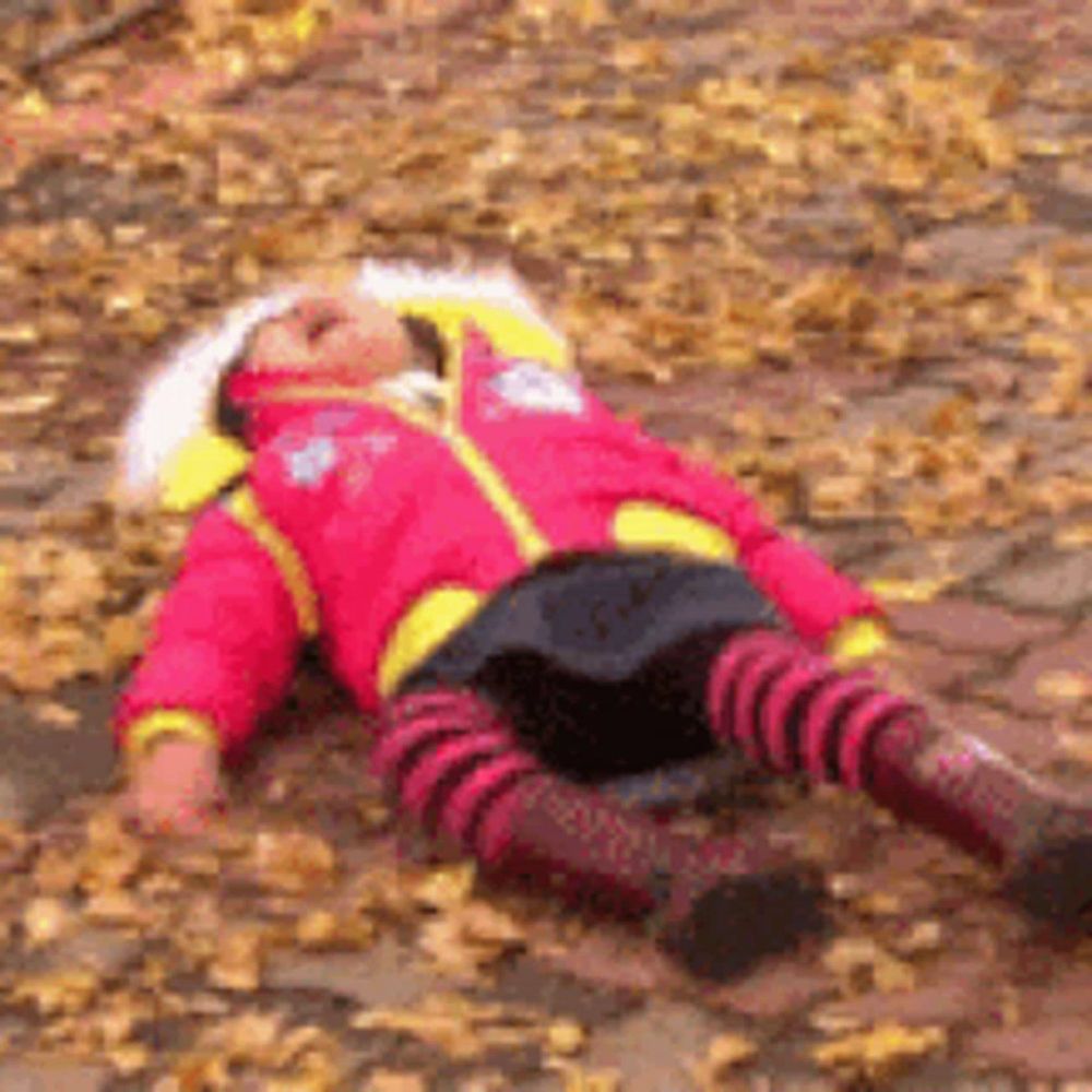 a little girl in a pink jacket is laying on the ground