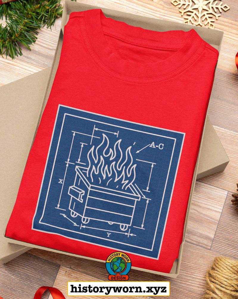 A red T-shirt is folded inside a gift box, featuring a blueprint-style white line illustration of a dumpster fire on a blue square. The scene is surrounded by holiday decorations. A small circular logo and the text “historyworn.xyz” appear below.
