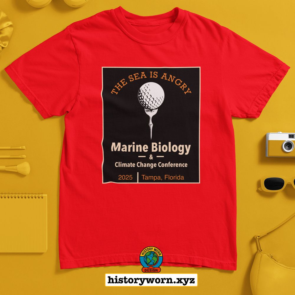 A red T shirt displays a bold black graphic featuring a golf ball on a tee with the text The Sea Is Angry. It promotes the 2025 Marine Biology and Climate Change Conference in Tampa, Florida. The shirt is shown on a yellow background with accessories.