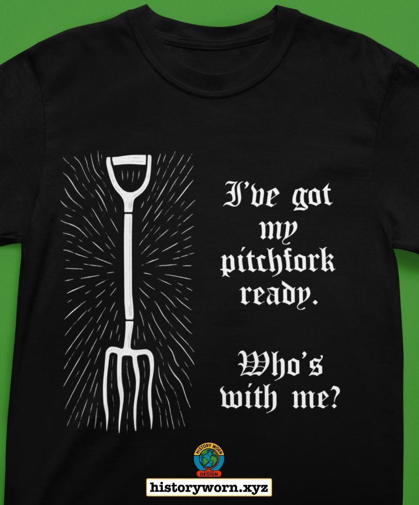 It is a black T shirt with a white drawing of a pitchfork on the left and white gothic text on the right that says “I’ve got my pitchfork ready. Who’s with me?” A small circular History Worn Design logo and the text historyworn.xyz appear at the bottom.