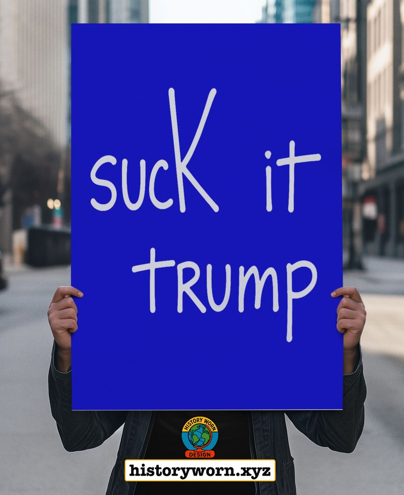 A person stands on a city street holding a large blue sign with handwritten white text that reads “suck it trump.”
