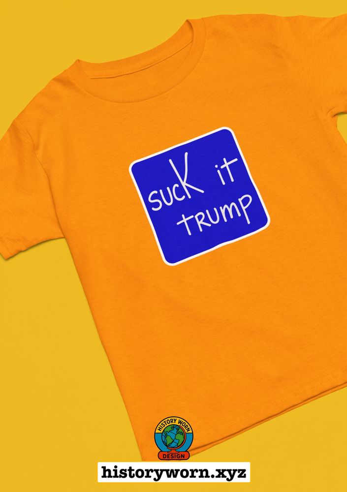 Orange t-shirt with a blue square graphic featuring white handwritten text that says “suck it trump”; bold political parody design with a retro quiz screen style. Shirt is laid flat on a solid orange background with “historyworn.xyz” branding at the bottom.