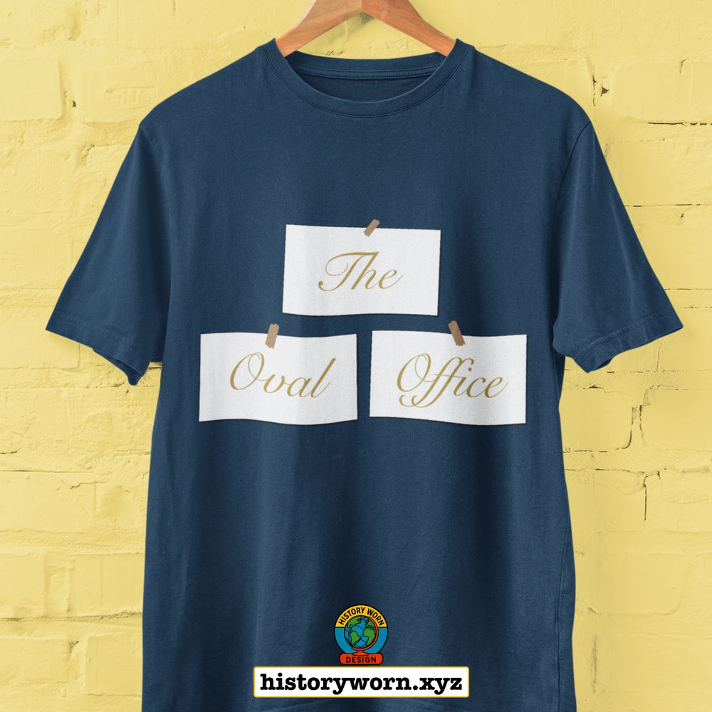 A navy blue t-shirt hangs on a wooden hanger against a yellow brick wall. It features three white cards with gold cursive text reading “The Oval Office,” arranged in a tiered layout. Below, a small logo and the website “historyworn.xyz” appear at the bottom center.