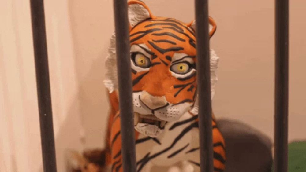 a statue of a tiger in a cage looking through bars