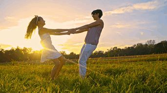 a man and a woman are holding hands in a grassy field