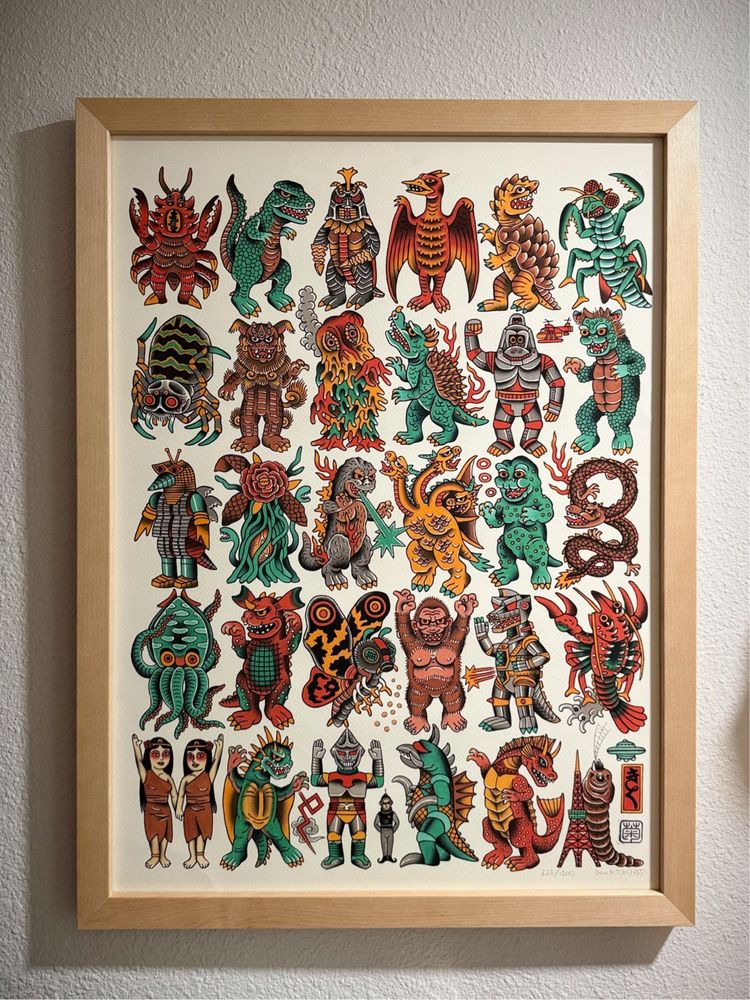 Framed artwork featuring a collection of colorful, stylized Kaiju illustrations. The monsters, depicted in a variety of vibrant colors such as green, red, and orange, include a mix of familiar and fantastical creatures with features like scales, wings, and claws. The artwork has a playful, cartoon-like style and is set against a plain white background, emphasizing the bold designs.