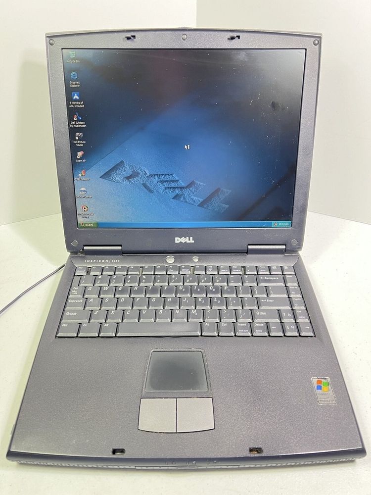 A Dell Inspiron 2650 displaying Windows XP with a Dell themed wallpaper on a dimly lit internal screen. 
