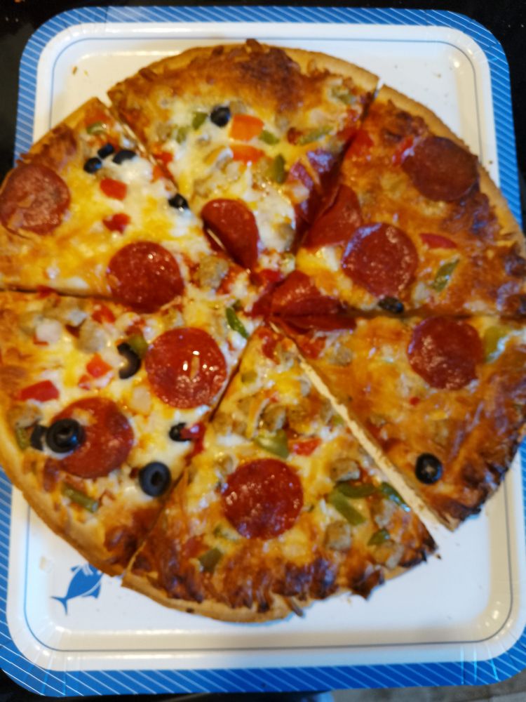 A picture of an entire pizza on a plate cut into six slices.