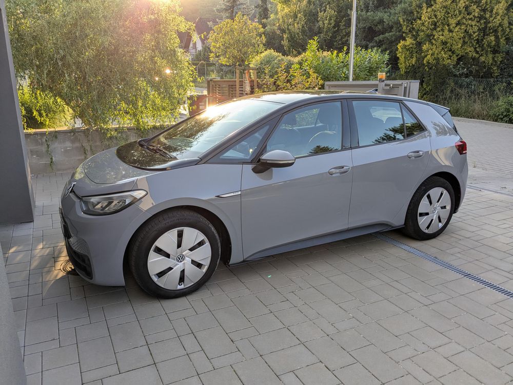 A grey Golf-sized car in front of a garage. A picture taken from the side.