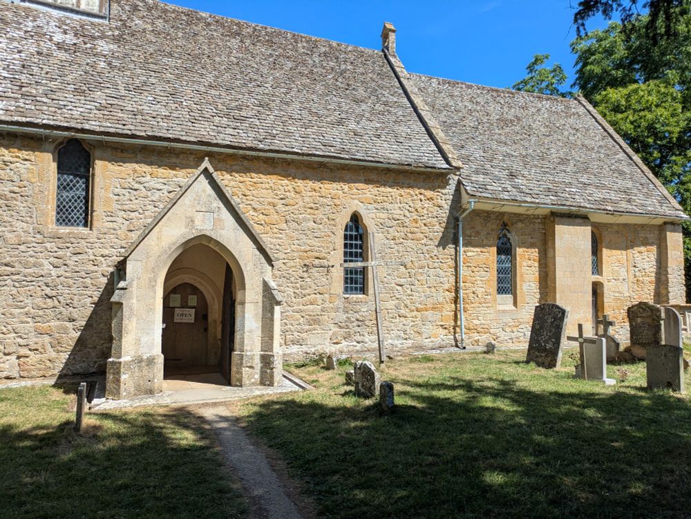 An angle looking further to the right capturing the rest of the church, with the main entrance on the left. There are some graves on the right hand of the image. 