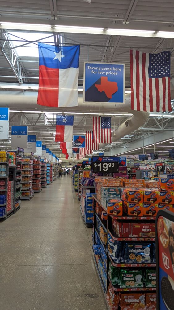 The inside of a Walmart with an American flag and a Texas flag hanging above every single isle.