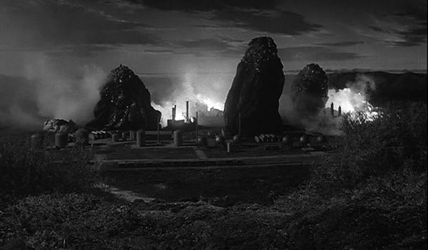 Giant alien slime monsters emerge from the flaming ruins of an industrial plant.  Movie Still from Quatermass 2, 1957