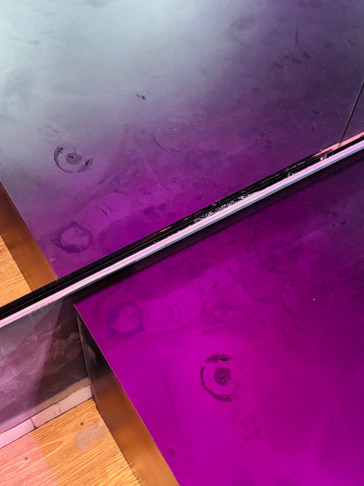 Foto de uma marca de PENISLONGO no pódio da sala de ginástica. No canto, logo no pé do espelho. 