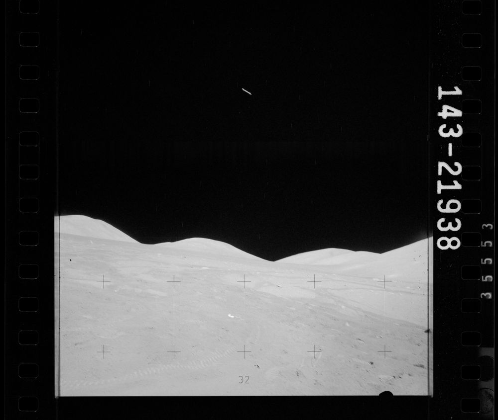 Apollo 17, photo number AS17-143-21938: a black and white, 1:1 photograph of the lunar surface. a single white stick-shaped object is visible high in the middle of the frame.