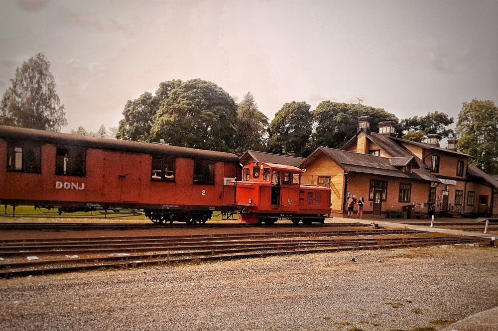 Old locomotive approaching the station, pulling a red and old wagon