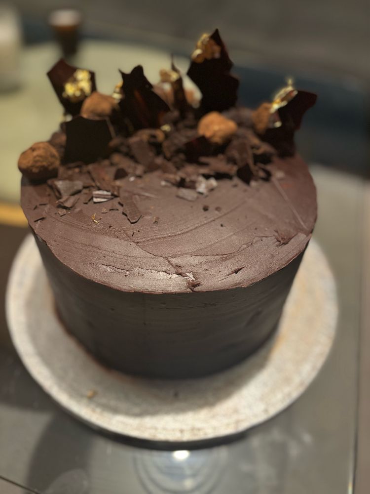 A big chocolate cake with chocolate truffles and chocolate shards on top
