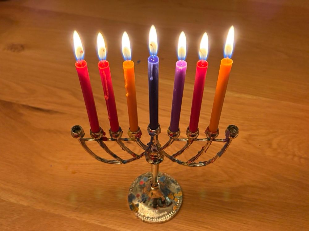 a silver menorah with seven lit candles on a wooden table 