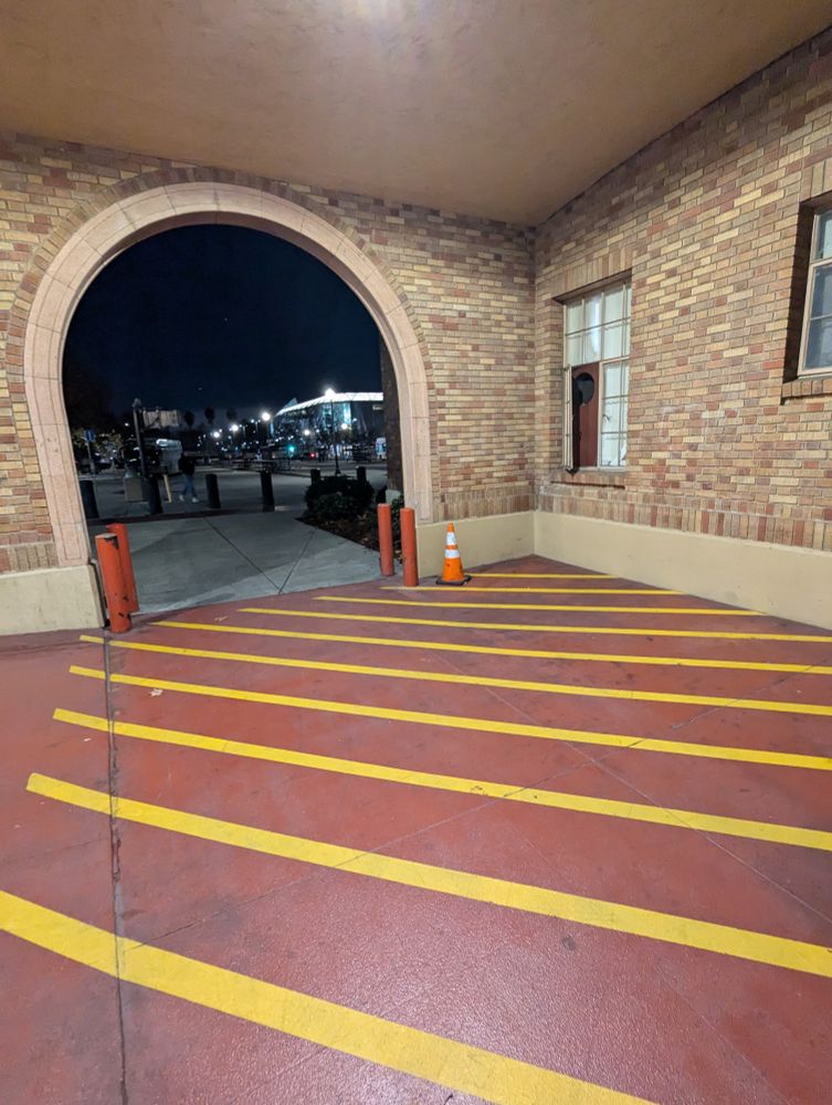 Photo of red concrete floor with parallel yellow stripes and brick archway