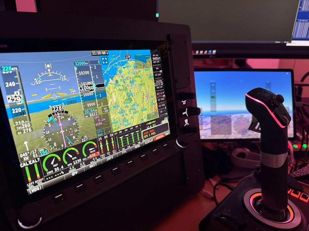 Photo of an engineer's desk with a Dynon's SkyView HDX avionix panel, an iPad running Infinite Flight, and a joystick.