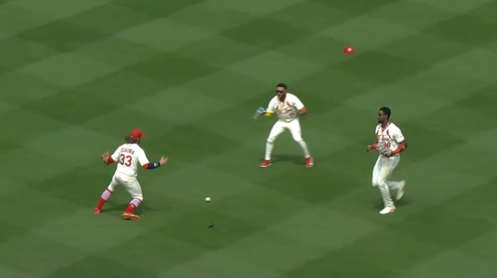 3 baseball players watch a fly ball land between them. one of their hats is flying like in mario odyssey.