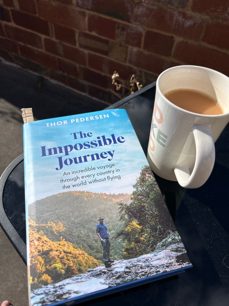 Photo of a book. The Impossible Journey by Thor Pedersen. And a cup of tea. 