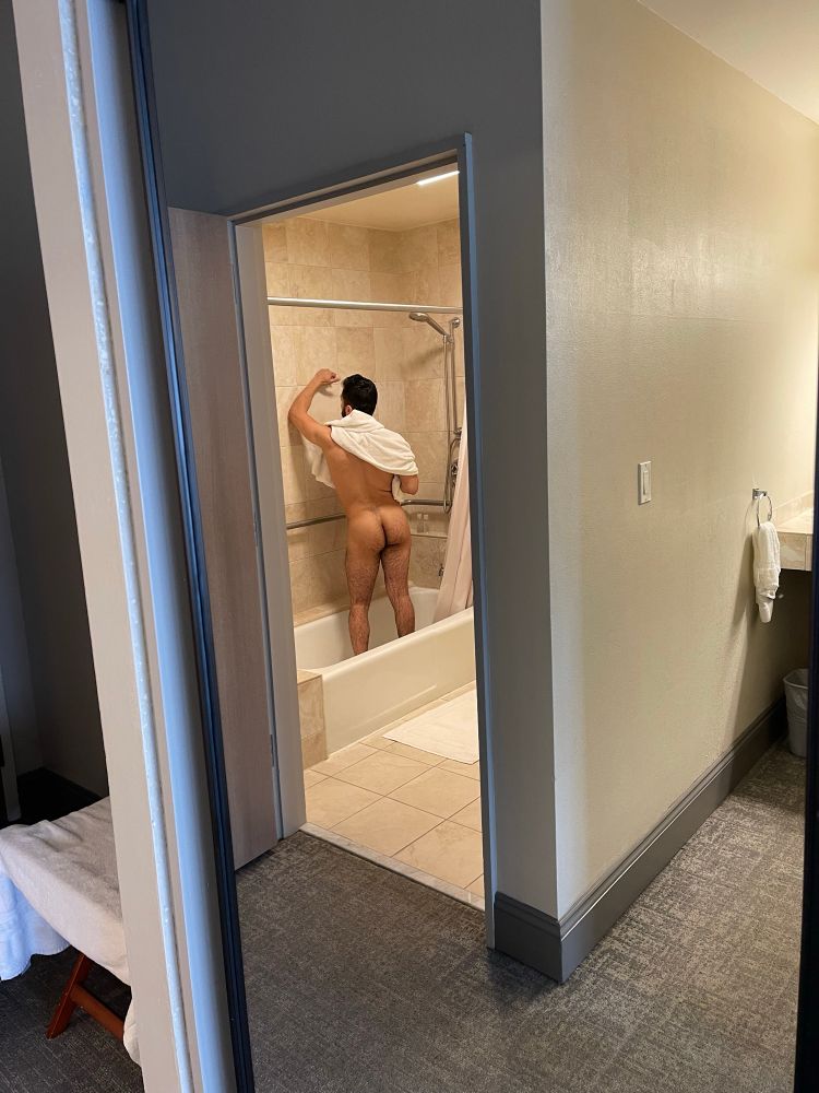 Picture taken of me in hotel shower from a distance, facing away from camera with towel over shoulders.