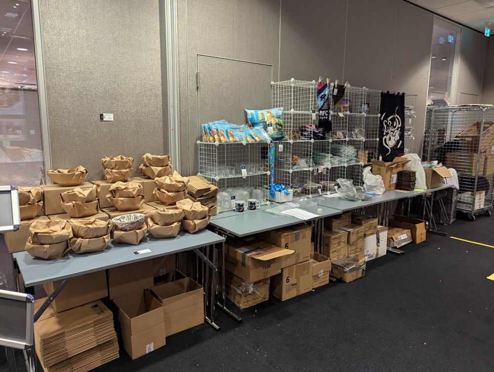 A picture of the room the Convention store was at during Nordic Fuzz Con 2025, displayed are items for sale an the quickly sold out Ramen Bowls that fit to the theme of the year