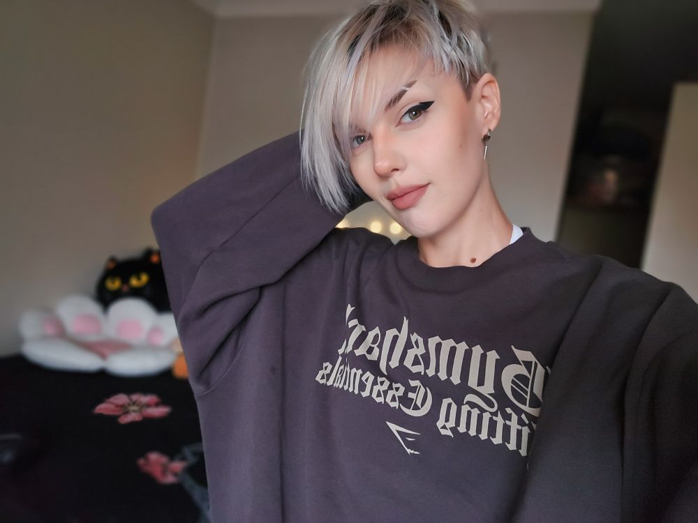 A selfie of Bonez dressed in a large comfy sweater.
Their hair is messy but their makeup looks fabulous.