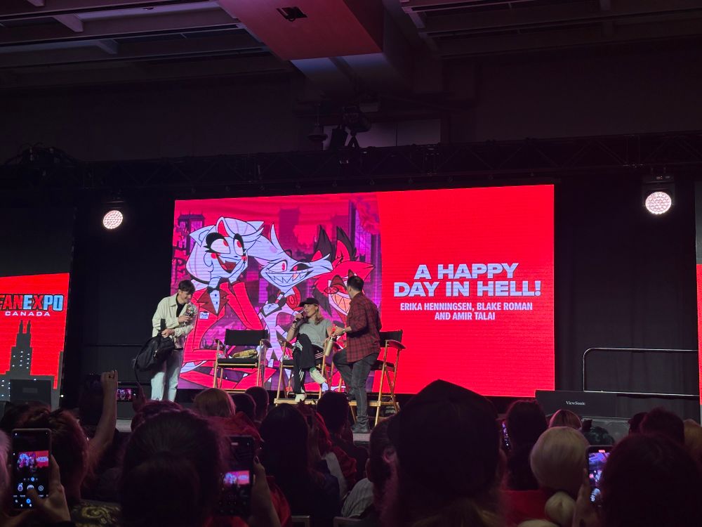 The voices of Angel Dust, Charlie and Alastair from Hazbin Hotel on stage. 